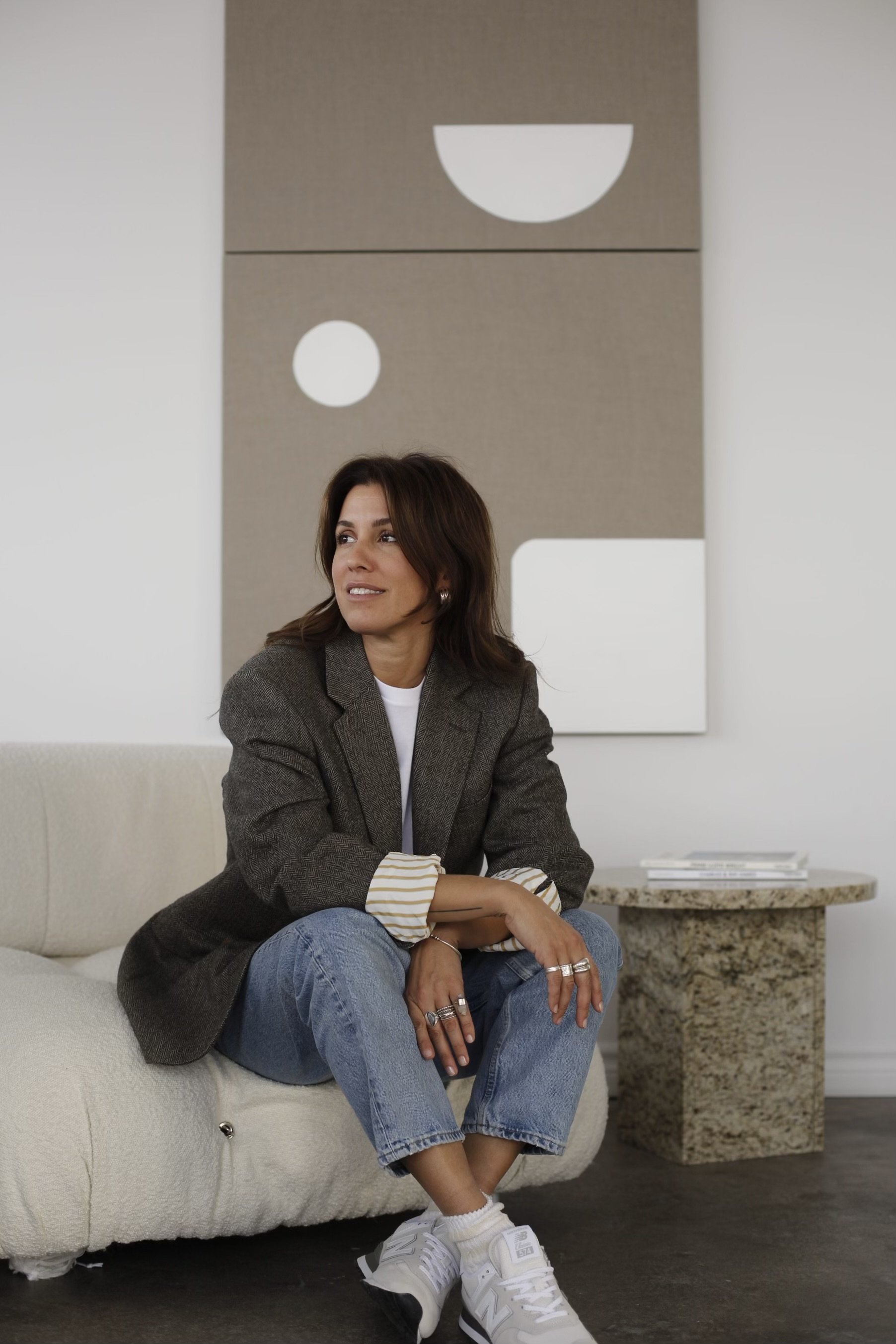 pia metni sitting on a light-coloured sofa in a room with abstract wall art