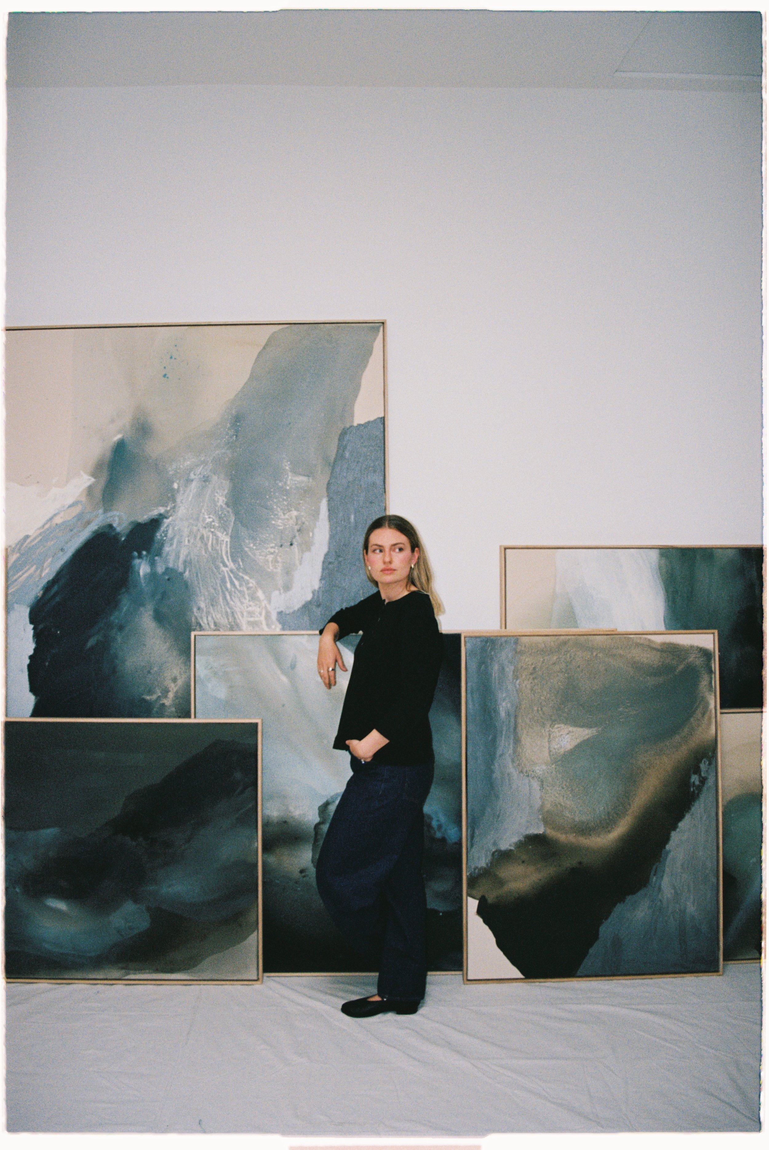 a woman standing in an art gallery surrounded by abstract paintings