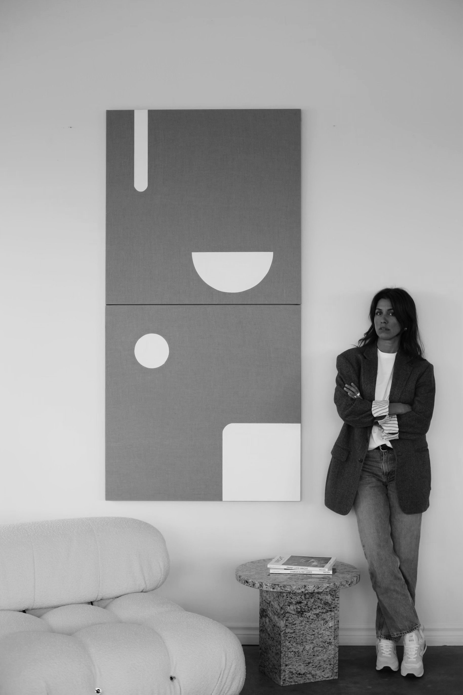 a woman leaning against a wall next to a modern abstract painting