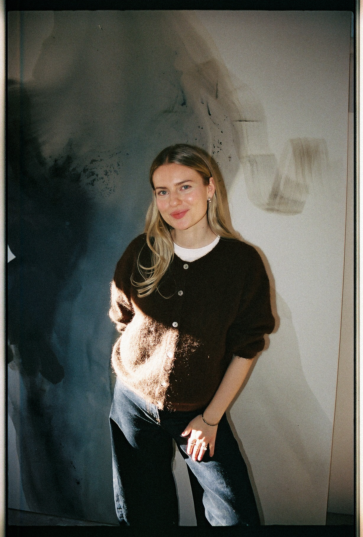 joy kinna standing in front of one of her paintings in her studio