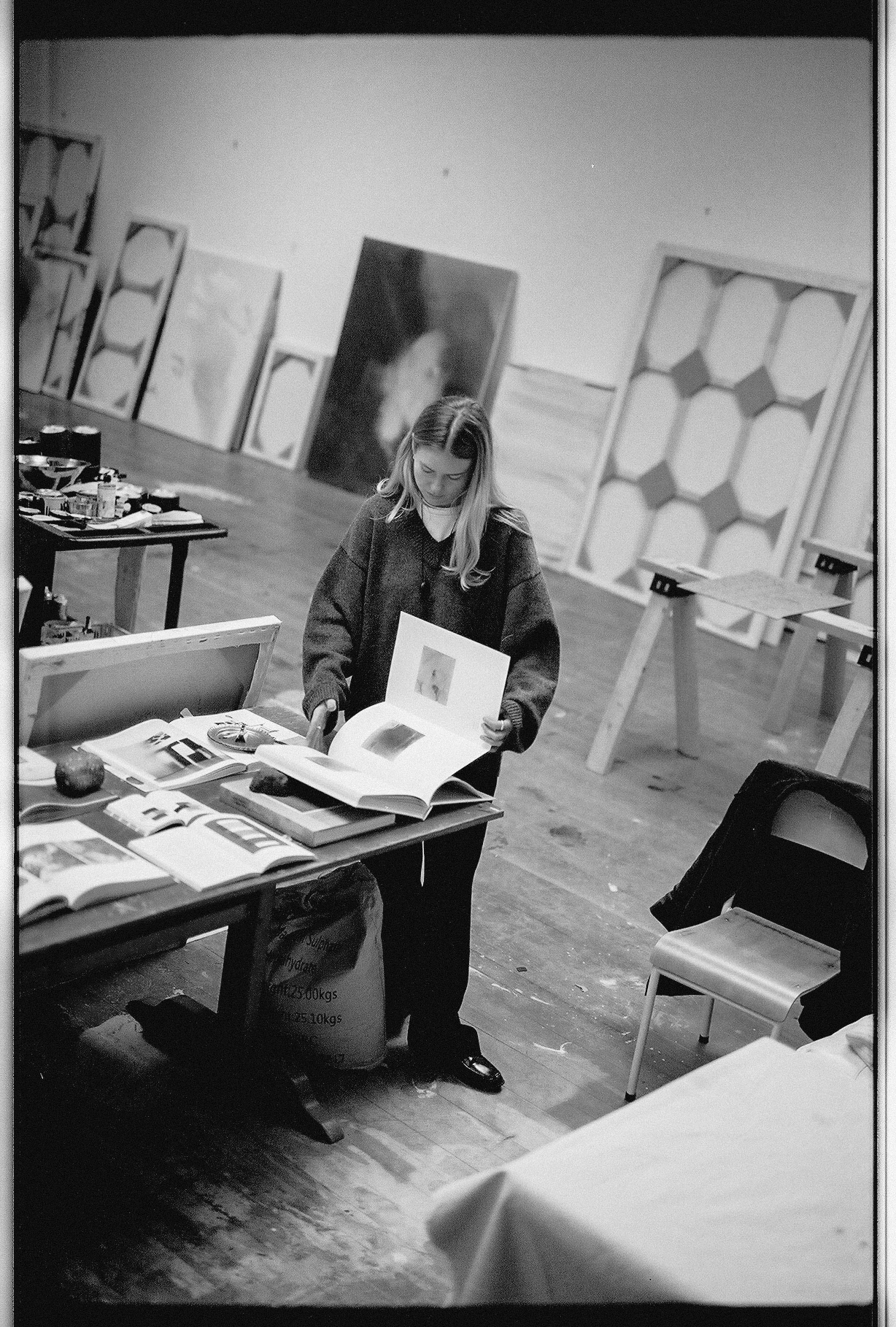 joy kinna reading in her studio, surrounded by canvases